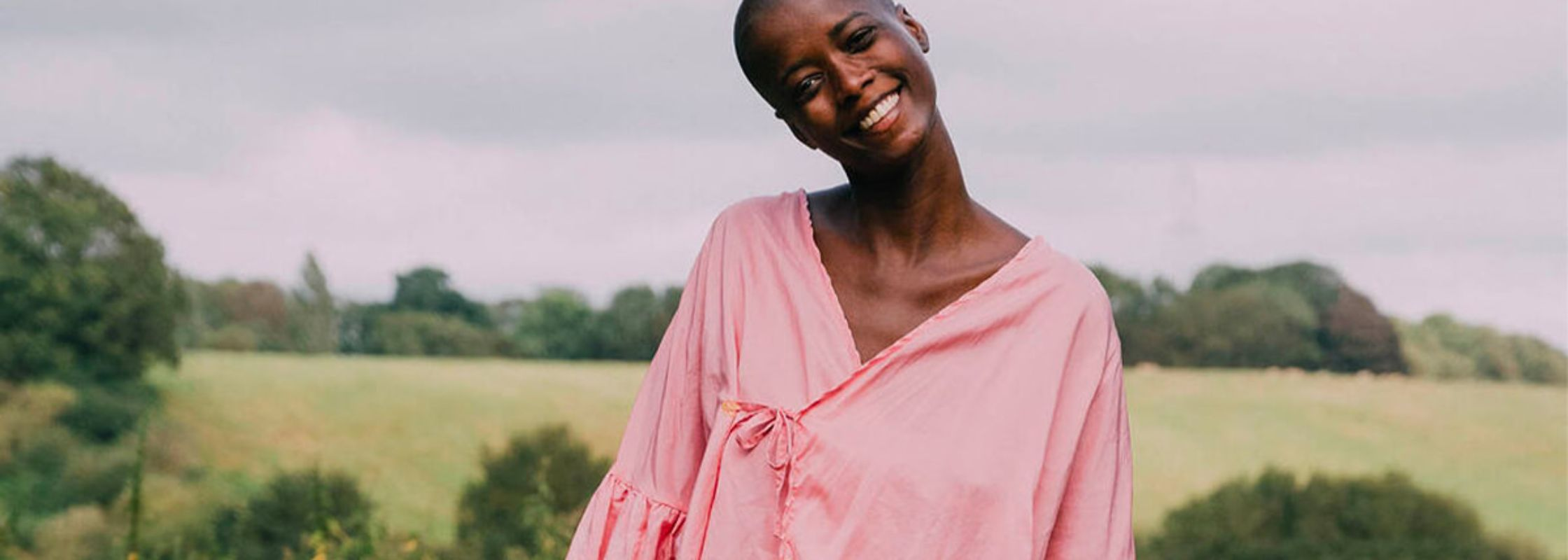 Model wearing a pink top with the British countryside in the background