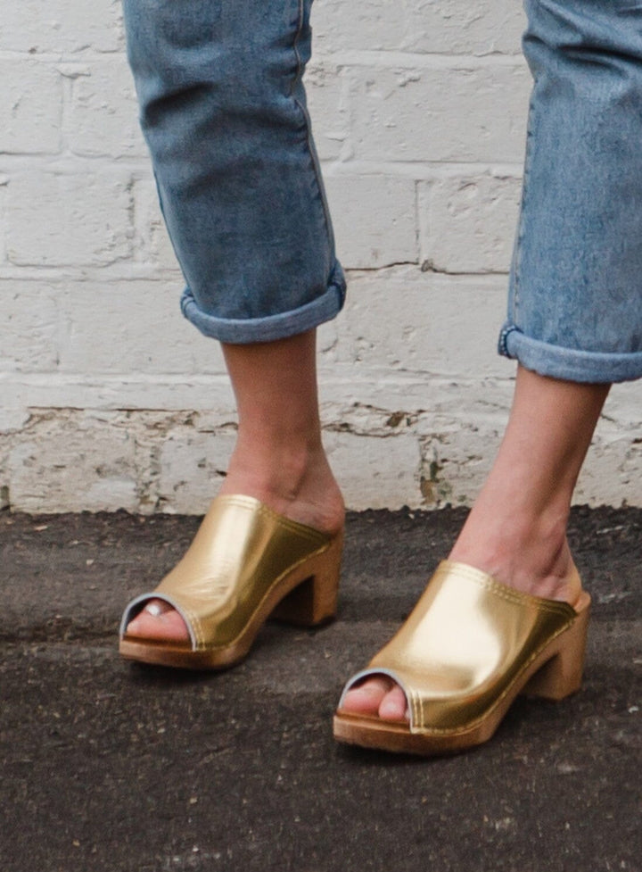 Calf shot of model wearing jeans and the mid Klassisk Sol Clog in Gold KIT + CLOGS   (Formally Kitty Clogs) 